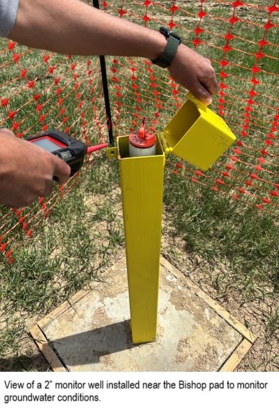 A yellow structure containing a well, hands using equipment to monitor the well