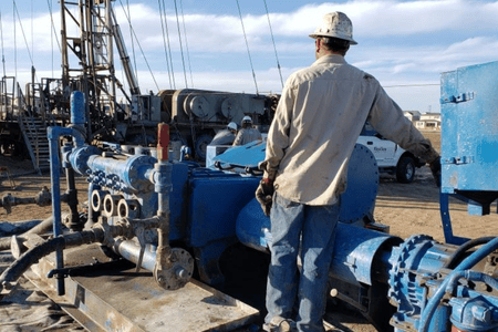 Man in a hardhat standing in front of rig