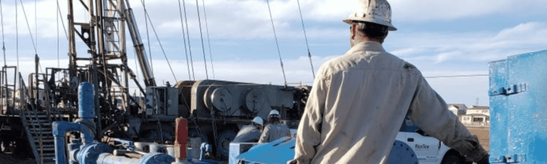 Man in a hardhat standing in front of rig.